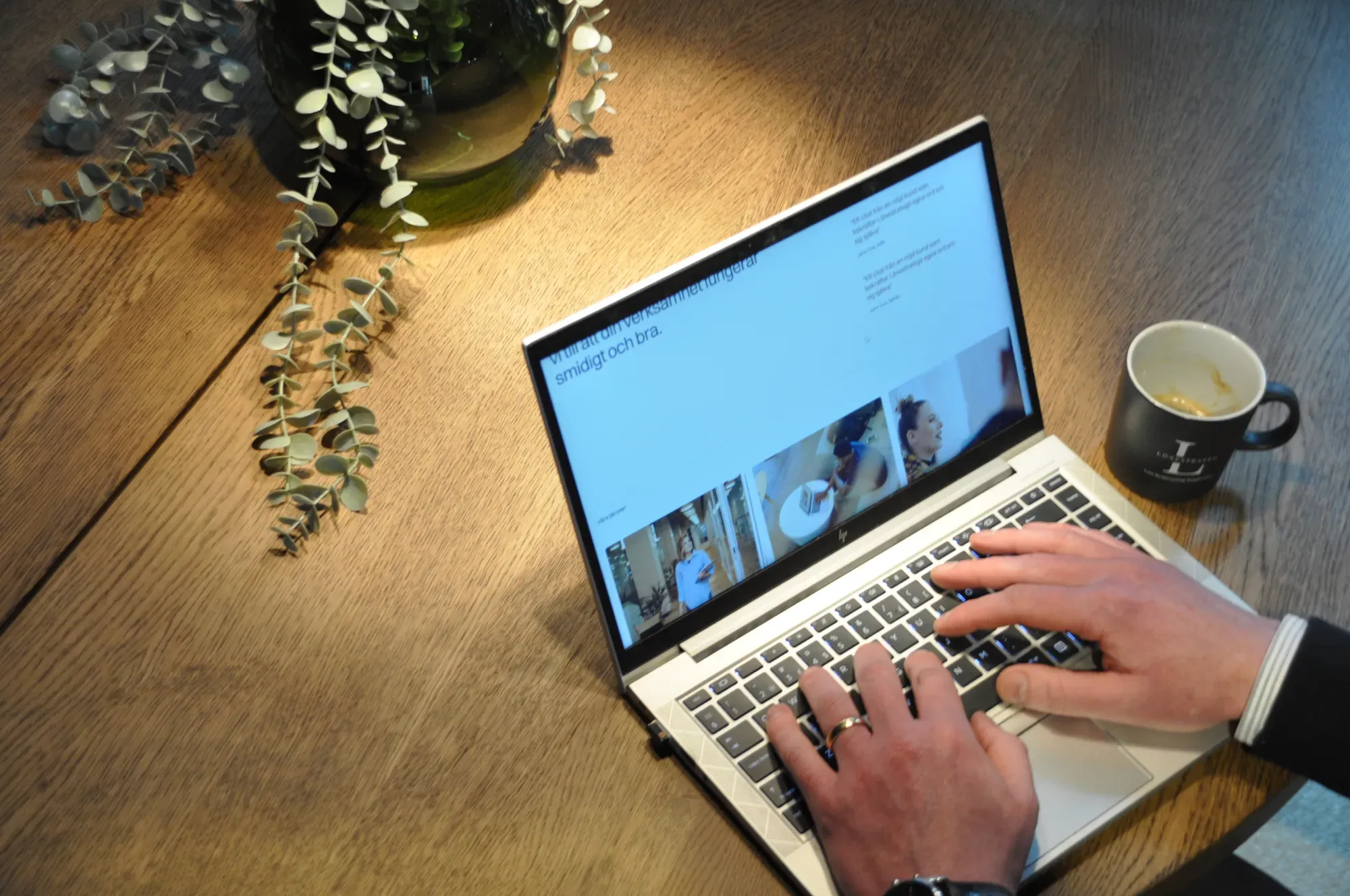 En dator på ett bord. Bredvid står en kaffekopp.